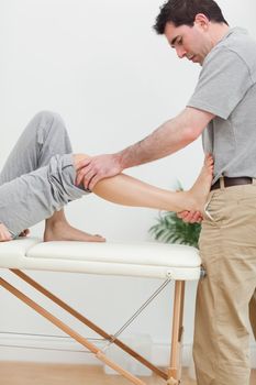 Brunette physiotherapist stretching a foot in a room