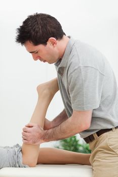 serious masseur massaging the leg of a woman in a room