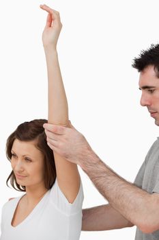 Serious doctor raising the arm of a woman in a room