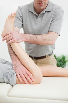 Close-up of a men stretching the leg of a woman in a room