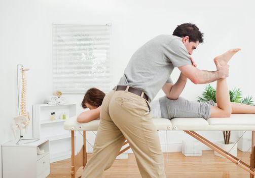 Brunette woman being stretched by a physiotherapist in a room