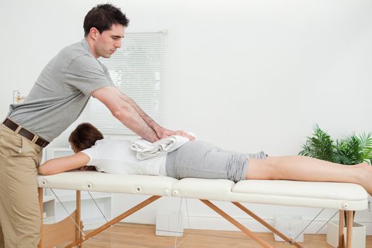 Woman lying while being massaged with a towel in a room