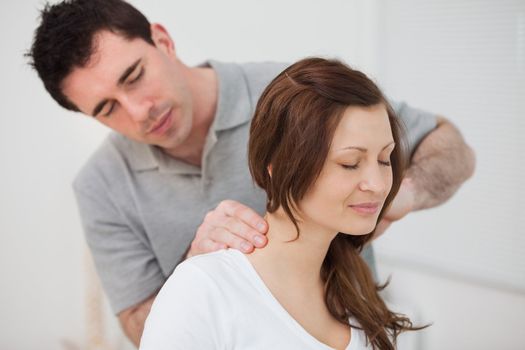 Smiling woman sitting while being massaged by a man in a room