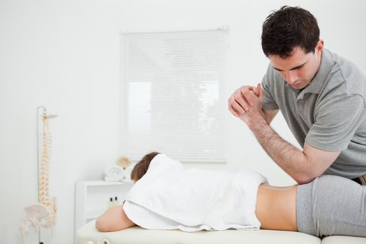 Brunette physiotherapist massaging a woman with his elbow in a room