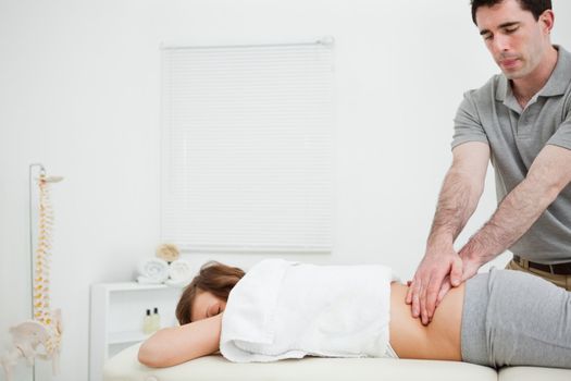 Masseur massaging the back of a brunette woman in a room