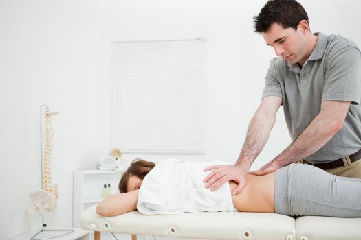 Serious practitioner massaging the lower back of a woman in a room