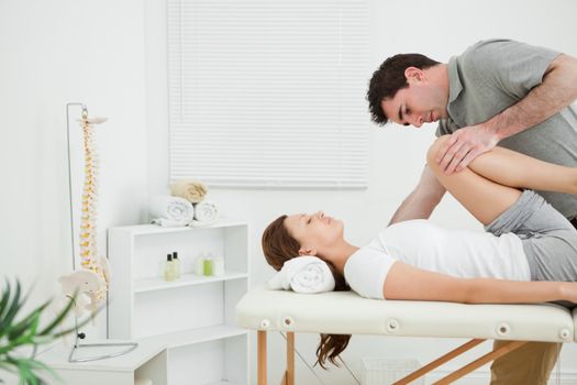 Brunette woman being stretched while she is lying in a room