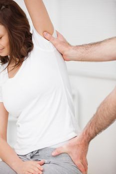 Close-up of a woman being stretched while sitting in a room