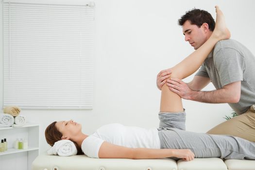 Man massaging a knee while placed it on his shoulder in a room