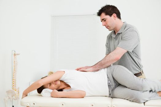 Brunette woman lying on the side while being massaged in a medical room