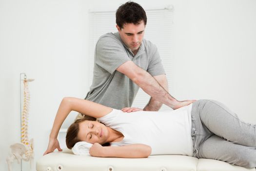 Osteopath crossing his arms while massaging a woman in his medical office