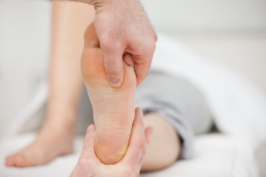 Practitioner placing his thumb on a foot in a medical room