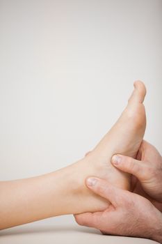 Two thumbs being placed on the side of a foot in a medical room