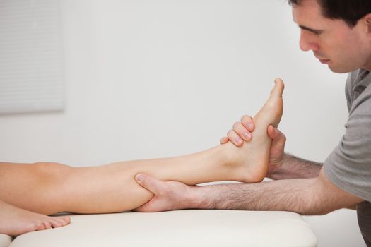 Serious physiotherapist holding the foot of a patient indoors