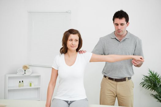 Serious practitioner extending the arm of a patient in a room