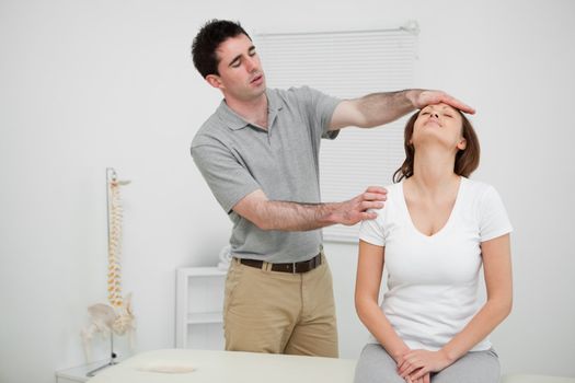 Serious practitioner placing his hand on the forehead of a woman in an office
