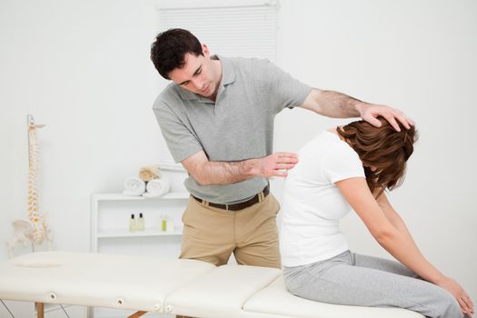 Physiotherapist looking at the spinal column of a woman in a medical room