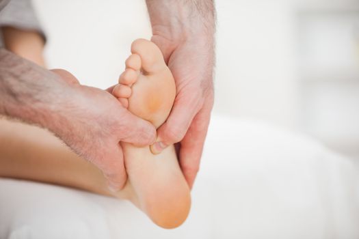 Physiotherapist using his fingers to massage a foot in a room