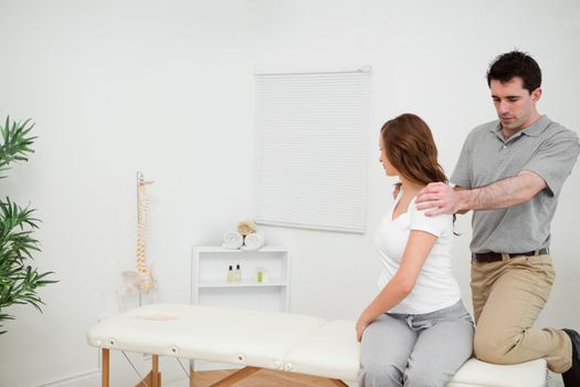 Osteopath looking at the back of a woman in a medical room
