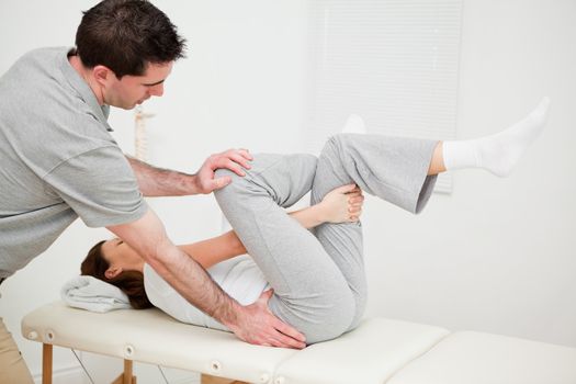 Woman holding her leg while being manipulated in a medical room