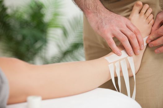 Doctor dressing an ankle in a room
