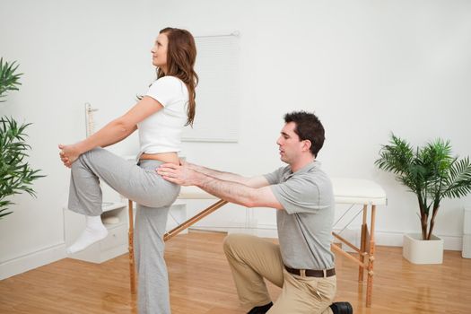 Serious woman stretching her leg in a room