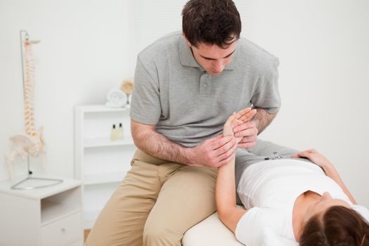 Serious physiotherapist holding the hand of a woman in a medical room