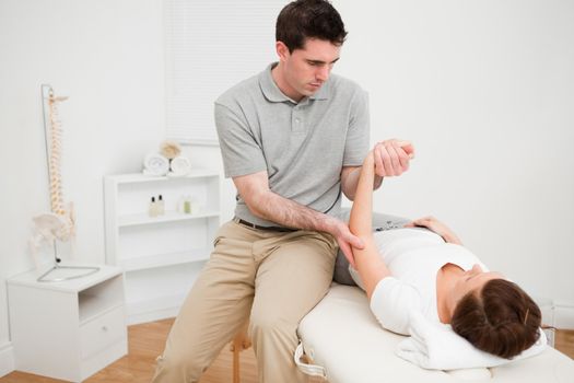 Physiotherapist holding the arm of a brunette woman in a room