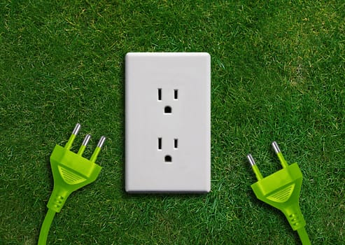 Green energy concept, Green power plug in electric outlet on a green grassland.