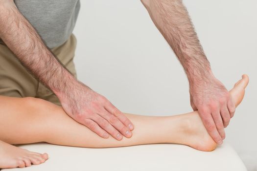 Physiotherapist touching the calf and the foot of a patient in a room