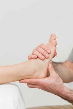 Hands of a physiotherapist massaging a foot in a room