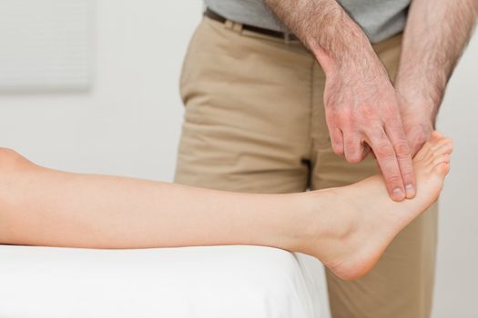 Fingers of a physiotherapist touching a foot in a room