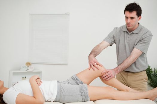 Serious doctor holding the knee of a woman in a room
