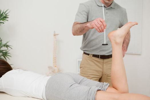 Serious doctor using a reflex hammer on his patient in a medical room