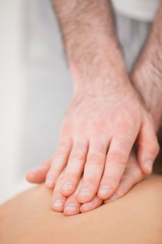 Osteopath massaging his patient while pressing his back in a room