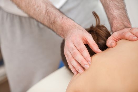 Chiropractor touching the back of his patient in a room