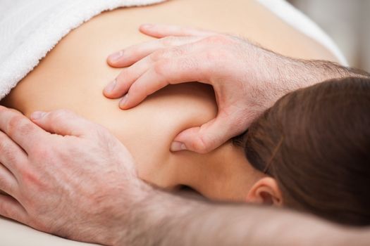 Osteopath massaging his patient while pressing his tumb in a room