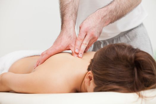 Therapist massaging the top of back of woman while standing in a room
