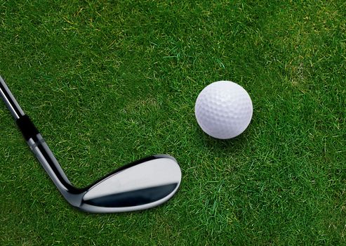 Golf ball and golf putter on green grass land .