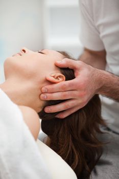 Neck of a woman being manipulating by a therapist in a room