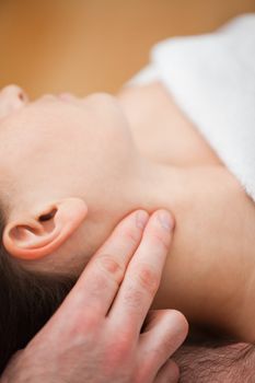 Close-up of doctor pressing two fingers on the neck of his patient indoors