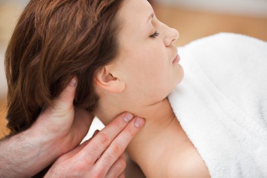 Therapist massaging the neck of woman while holding her head in a room