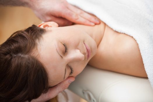 Doctor holding the head of a woman while massaging her neck in a room