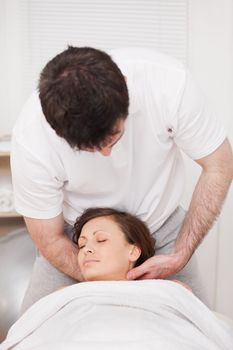 Therapist massaging the neck of a woman while holding her head in a room