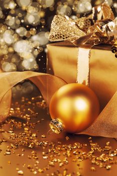 golden christmas ball near christmas present with beautiful sparkling bokeh 