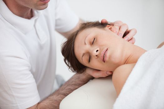 Woman being massaging by the doctor while having the head turn in the side inddor