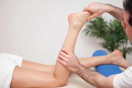 Doctor manipulating the leg of his patient  in a room