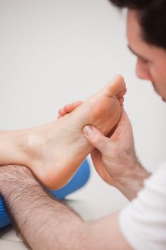 Reflexologist massaging the foot of his patient in a room