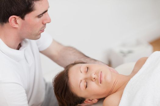 Masseur massaging the neck of his patient  in a room