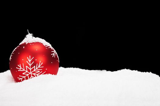 red christmas ball in snow with black background